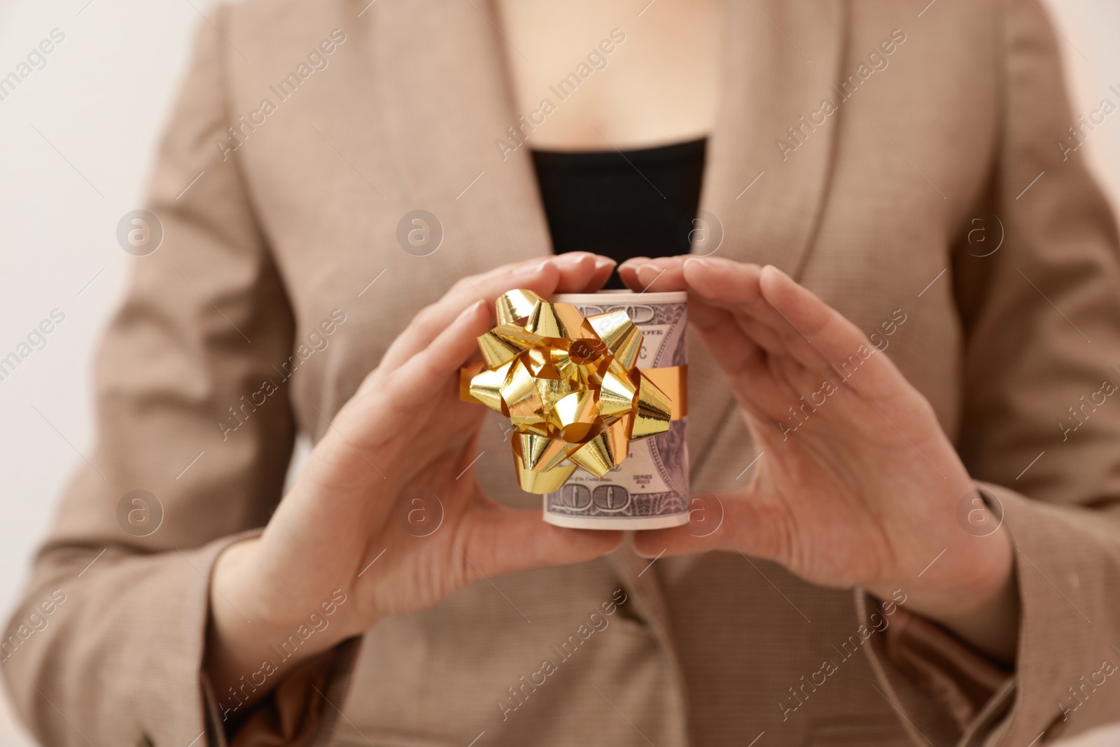 Photo of Woman holding bundle of dollars tied with ribbon, closeup