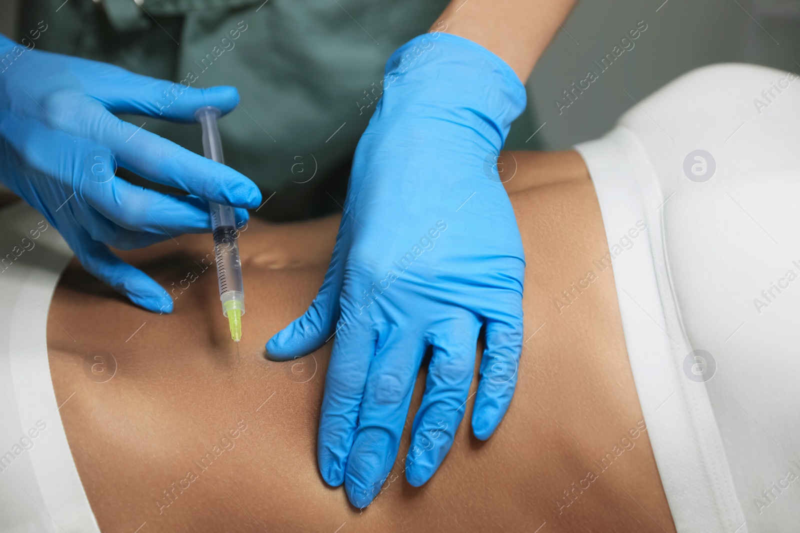 Photo of Young woman getting belly injection in salon, closeup