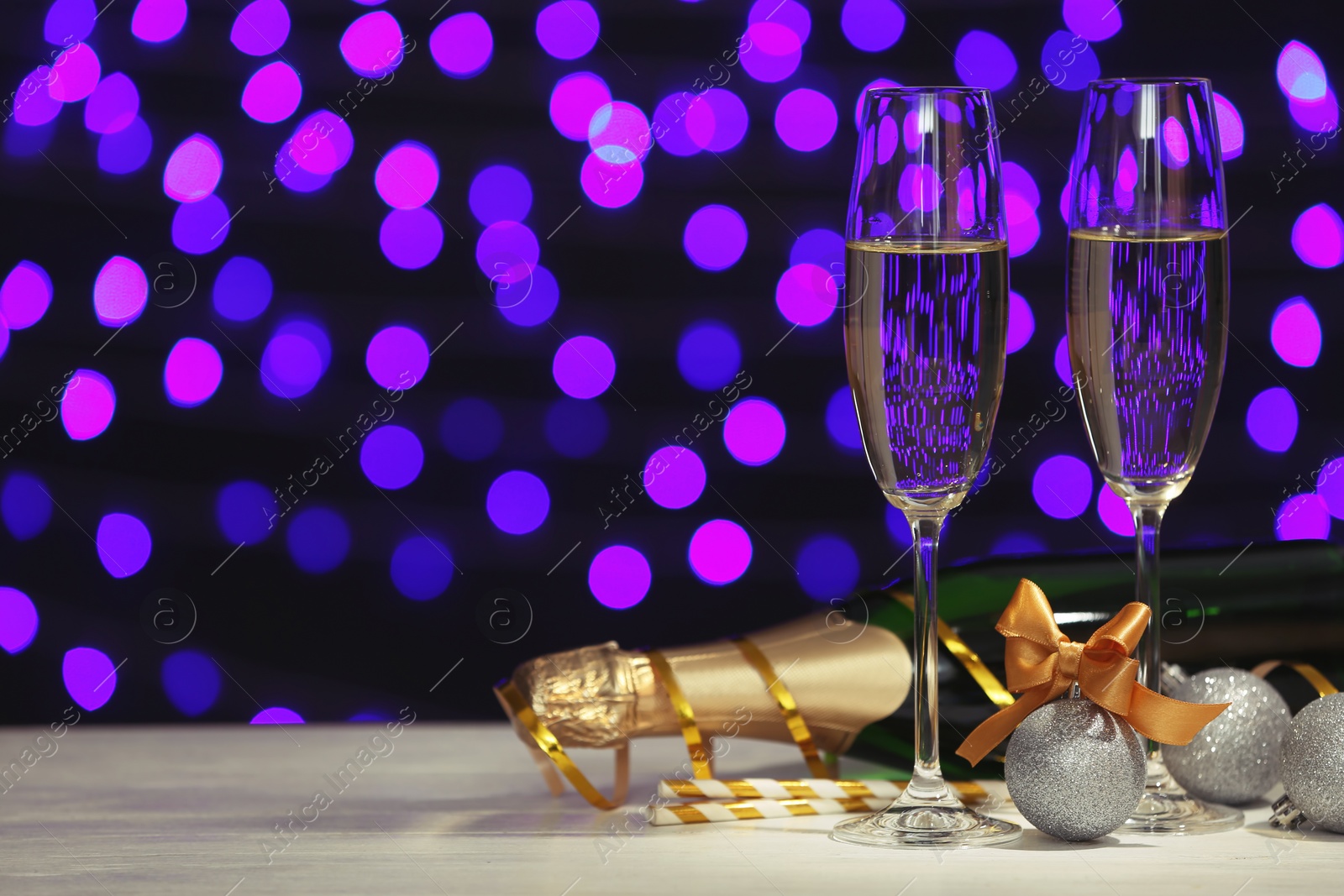 Photo of New year composition with champagne and space for text against blurred Christmas lights