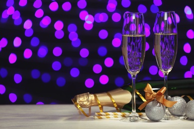 New year composition with champagne and space for text against blurred Christmas lights