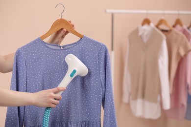 Photo of Woman steaming blouse on hanger at home, closeup. Space for text