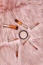 Flat lay composition with makeup brushes and powder on faux fur