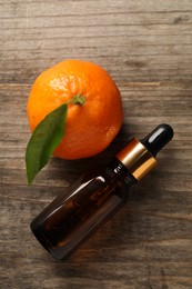 Photo of Bottle of tangerine essential oil and fresh fruit on wooden table, flat lay