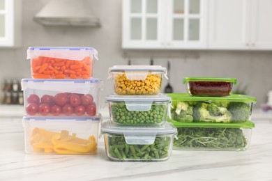 Photo of Glass and plastic containers with different fresh products on white marble table in kitchen. Food storage