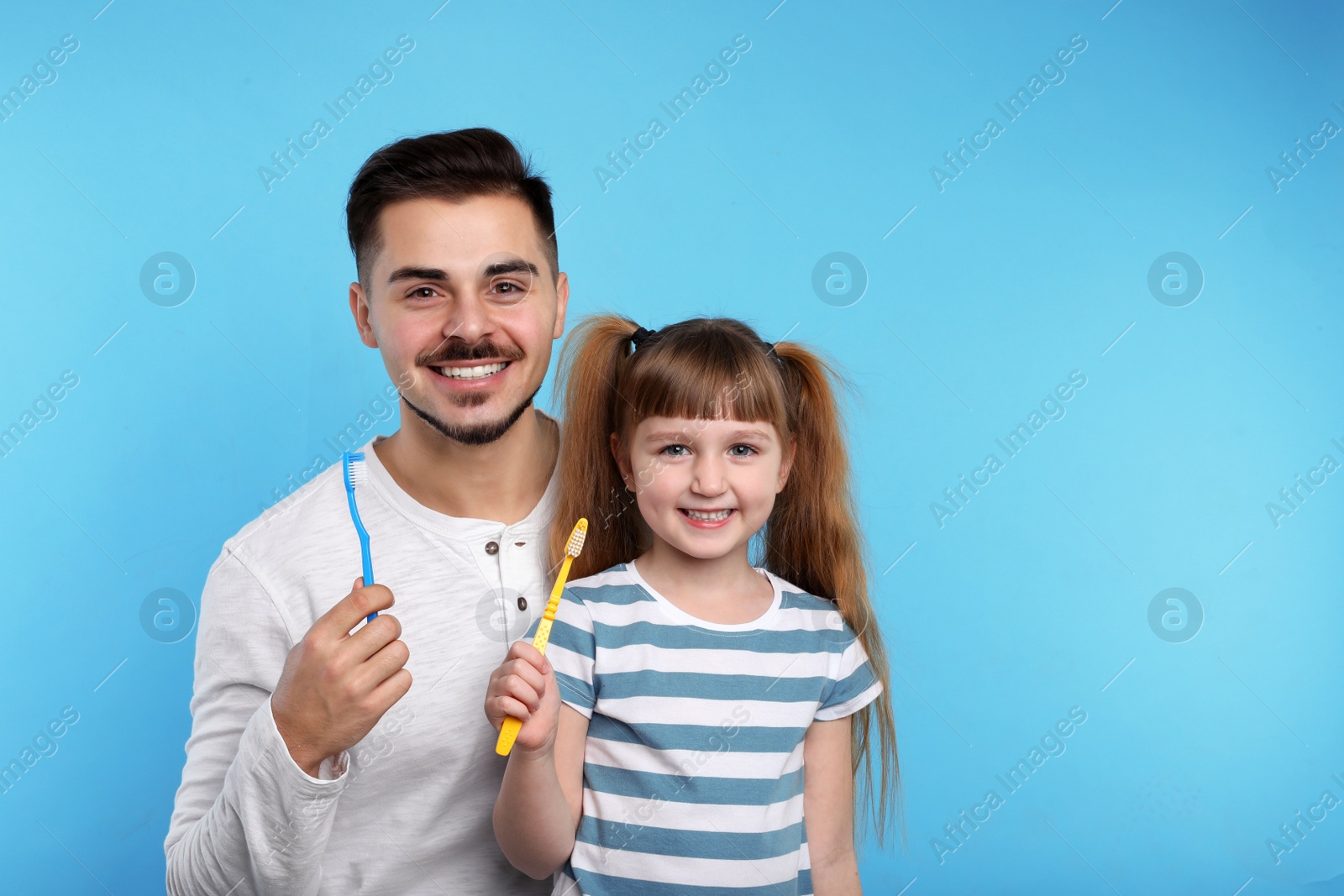 Photo of Little girl and her father with toothbrushes on color background, space for text. Teeth care