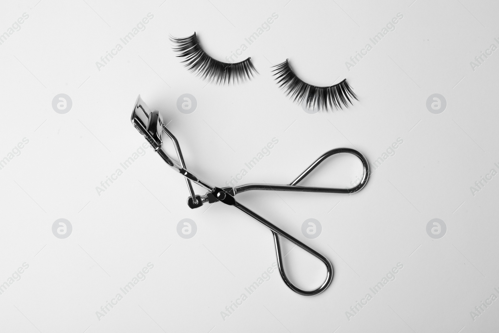 Photo of Flat lay composition of curler and false eyelashes on white background