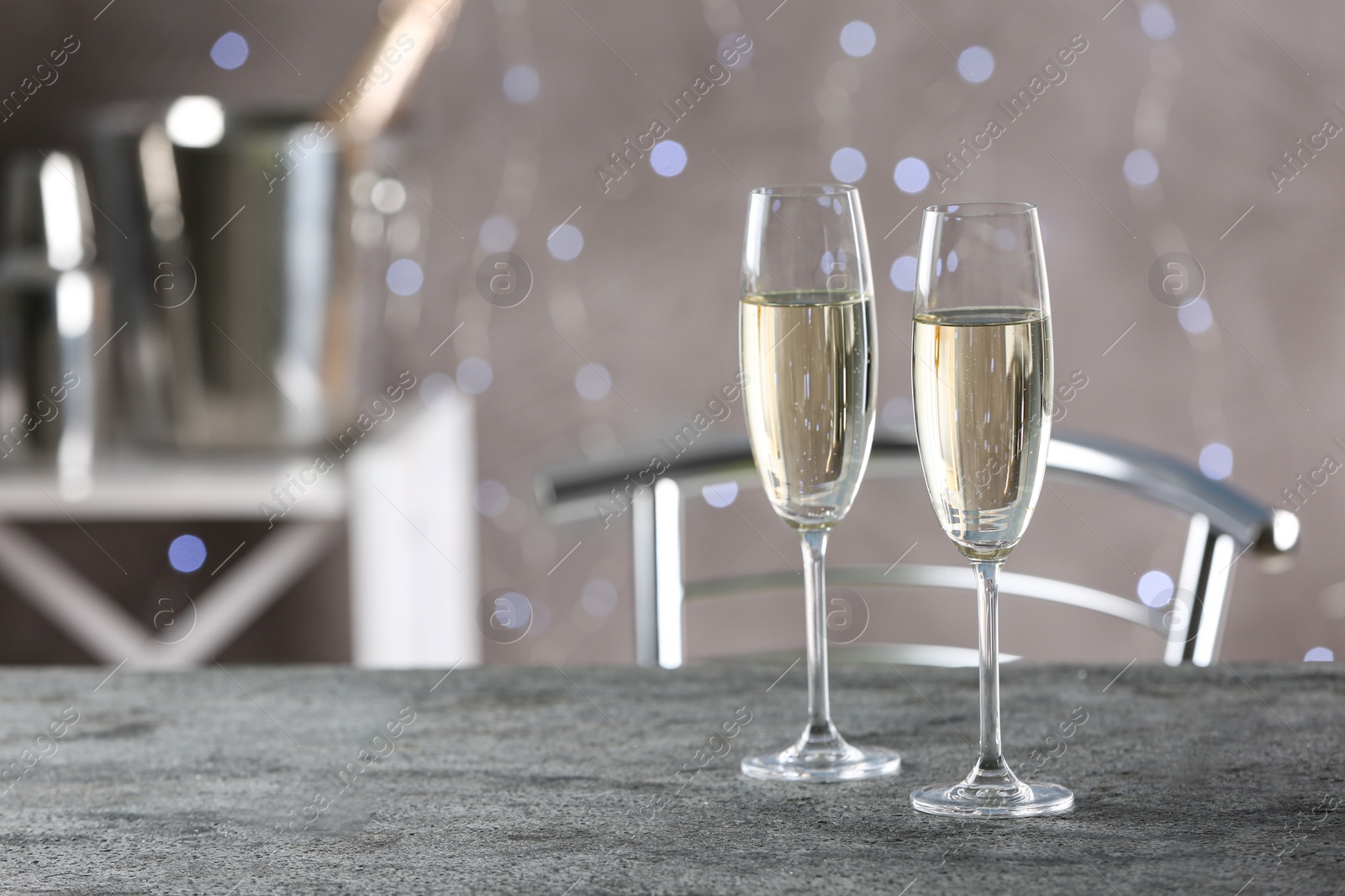Photo of Glasses of champagne on grey table. Space for text