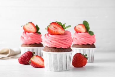 Photo of Sweet cupcakes with fresh strawberries on white table
