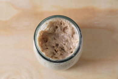 Photo of Sourdough starter in glass jar on wooden table, top view