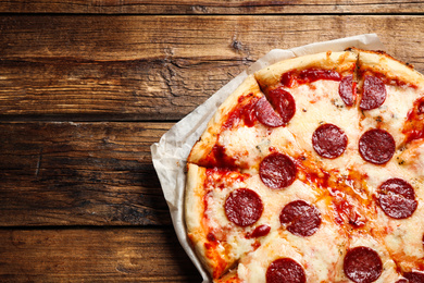 Hot delicious pepperoni pizza on wooden table, top view. Space for text