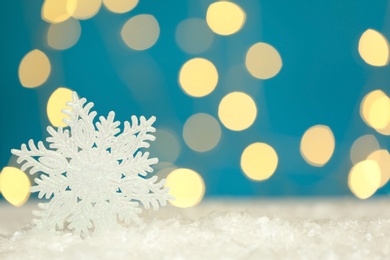 Photo of Beautiful decorative snowflake against blurred festive lights. Space for text