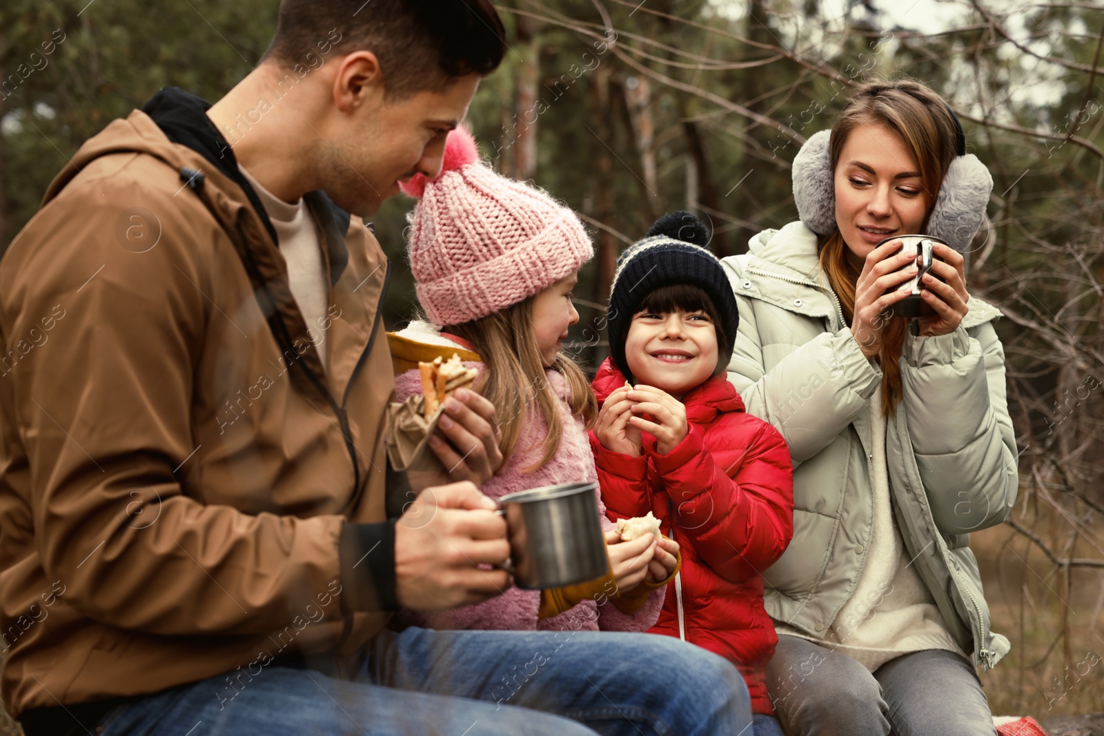 Photo of Happy family with sandwiches and hot drinks spending time together in forest