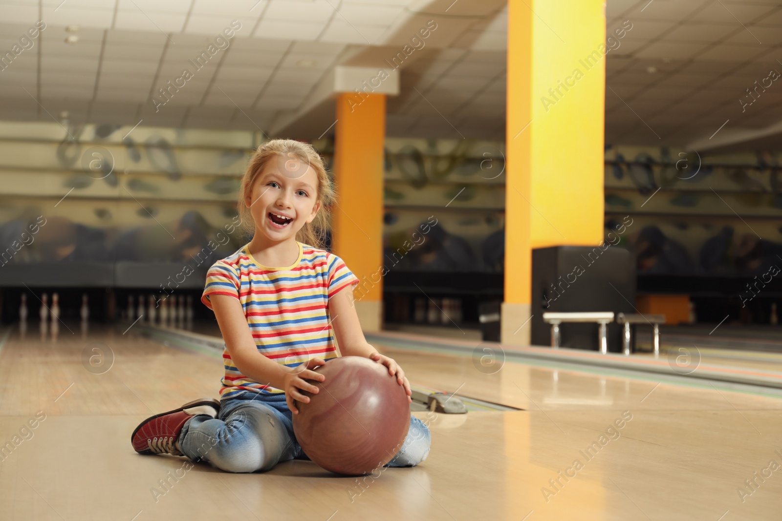 Photo of Little girl with ball in bowling club