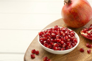 Photo of Ripe juicy pomegranate grains on white wooden table. Space for text