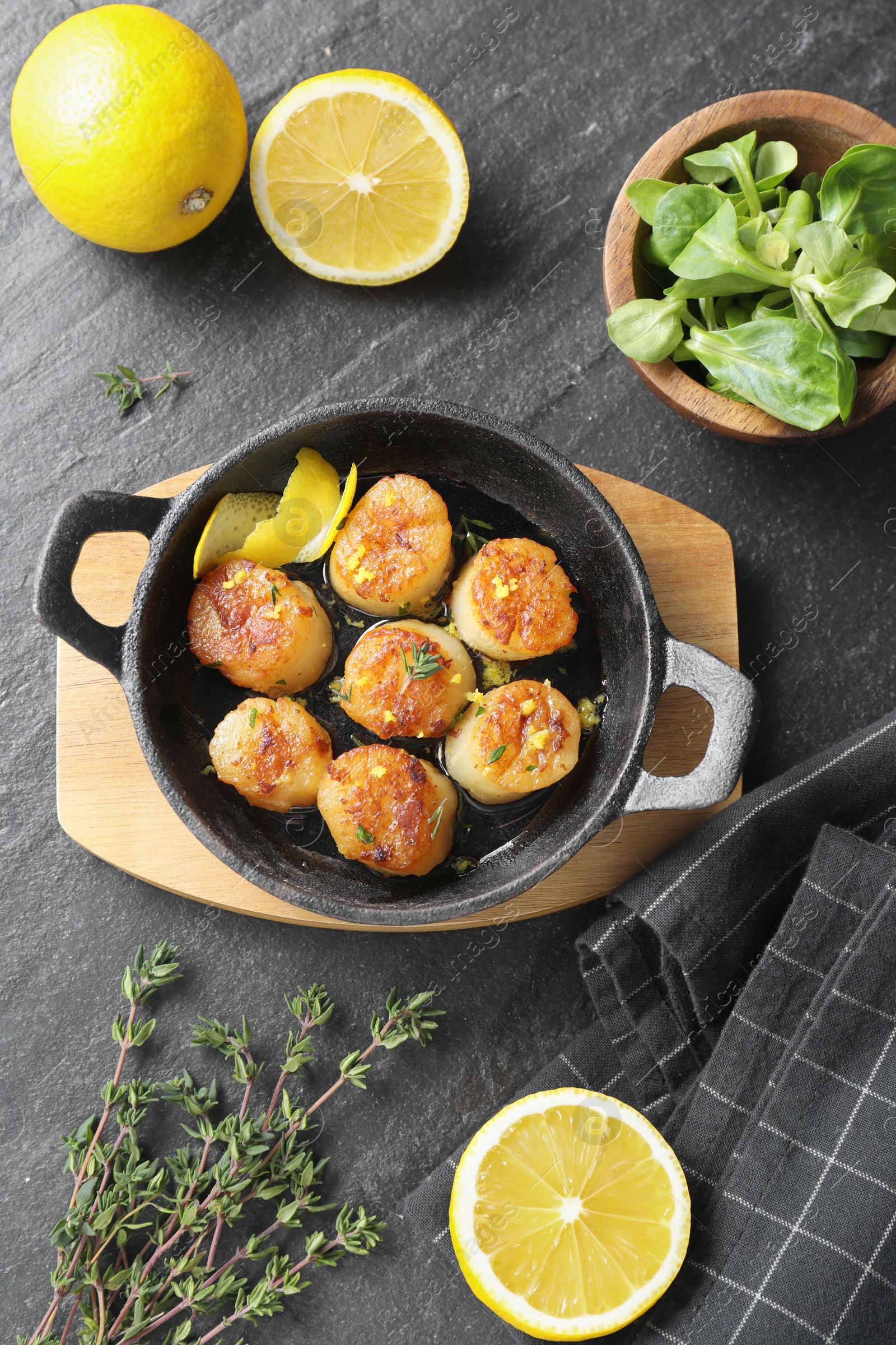 Photo of Delicious fried scallops and ingredients on dark gray textured table, flat lay