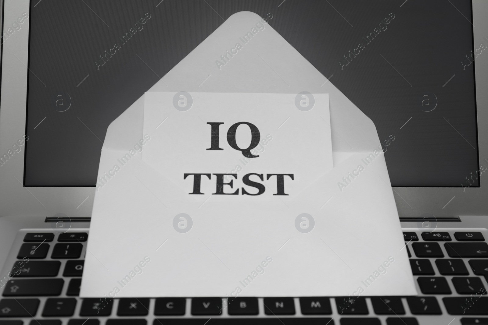 Photo of Paper with words IQ Test in envelope on laptop