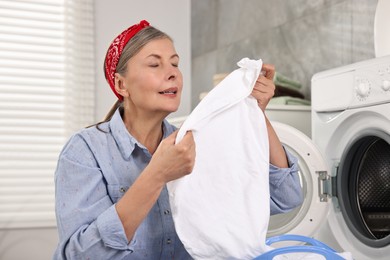 Photo of Housewife with laundry near washing machine at home