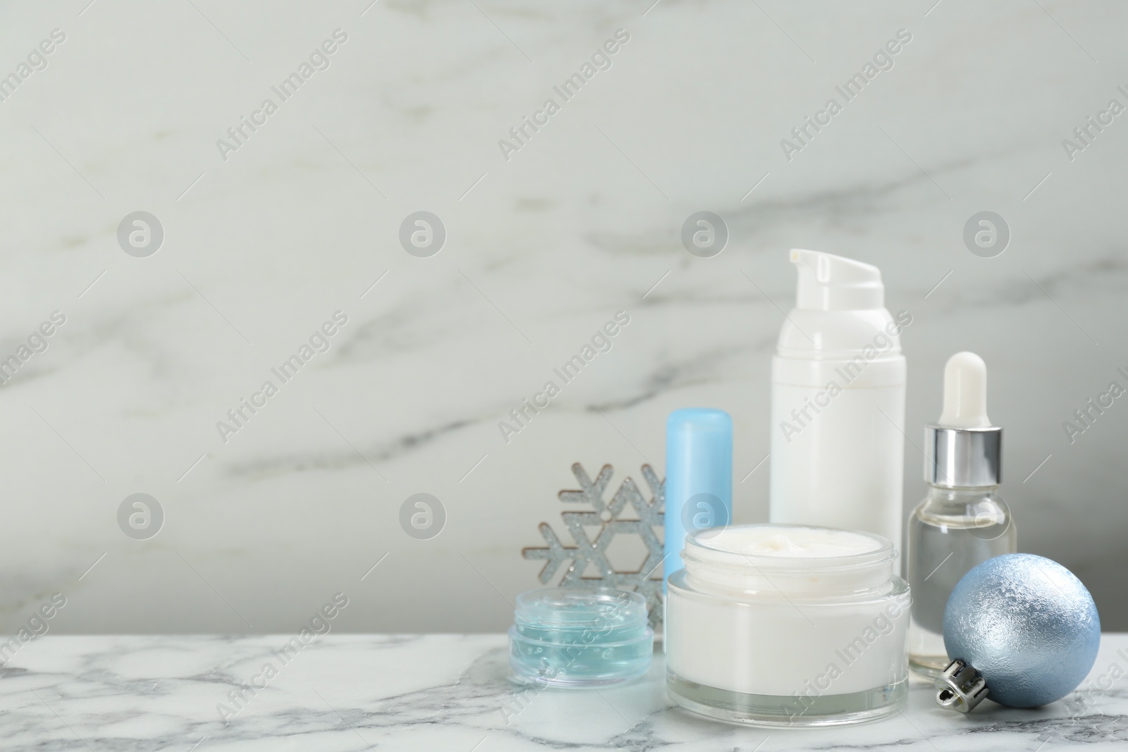 Photo of Beautiful composition with cosmetic products on white marble table, space for text. Winter care