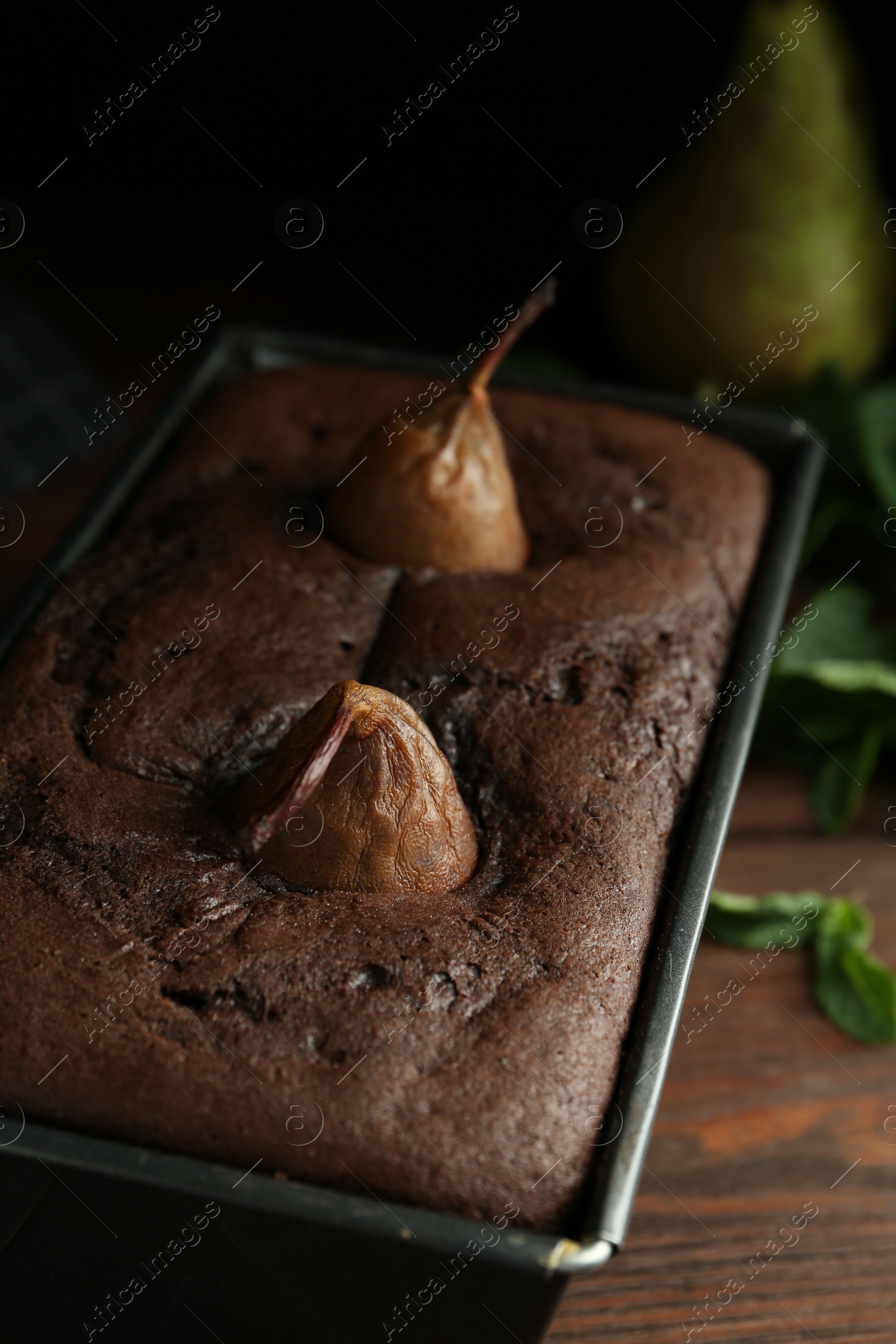 Photo of Tasty pear bread in baking form on wooden table. Homemade cake