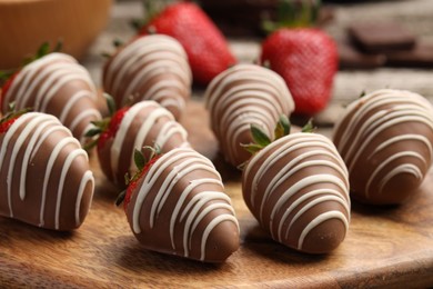 Photo of Delicious chocolate covered strawberries on wooden board, closeup