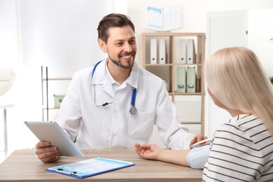 Photo of Doctor checking mature woman's pulse with medical device in hospital