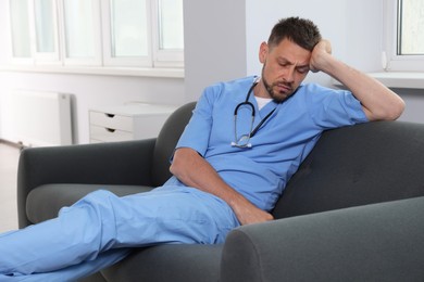Photo of Exhausted doctor resting on sofa in hospital