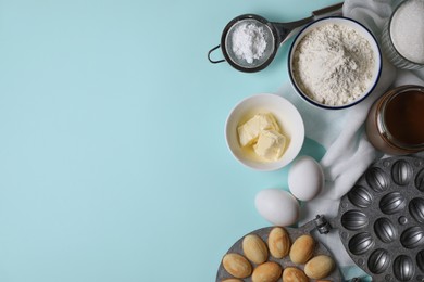 Photo of Freshly baked homemade walnut shaped cookies, baking mold and ingredients on turquoise table, flat lay. Space for text