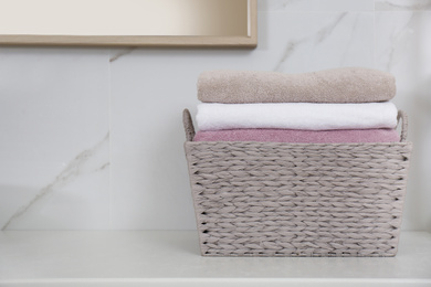 Photo of Laundry basket with fresh towels on counter in bathroom