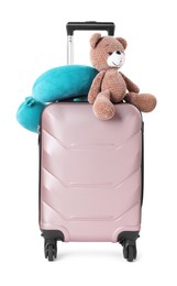 Photo of Light blue travel pillow and toy bear on suitcase against white background