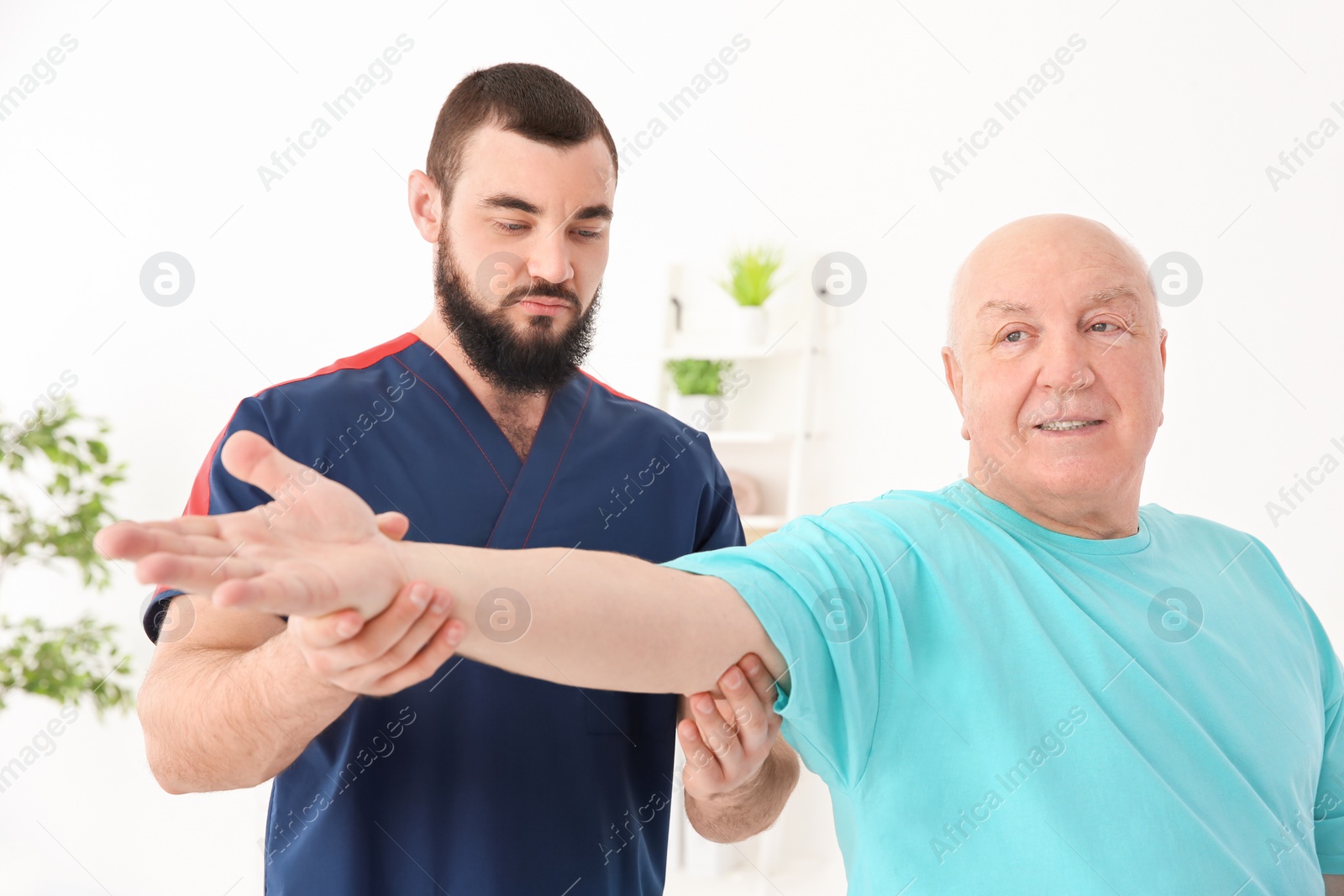 Photo of Young physiotherapist working with senior patient in clinic