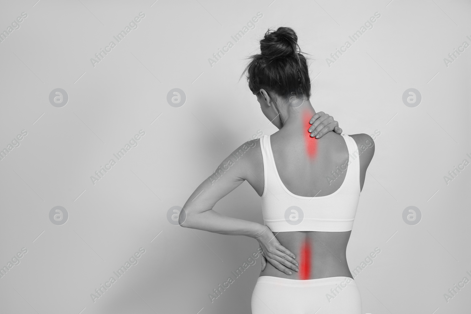 Image of Woman suffering from back pain on light background, space for text