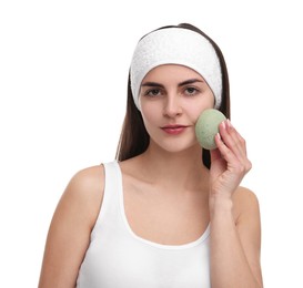 Photo of Young woman with headband washing her face using sponge on white background