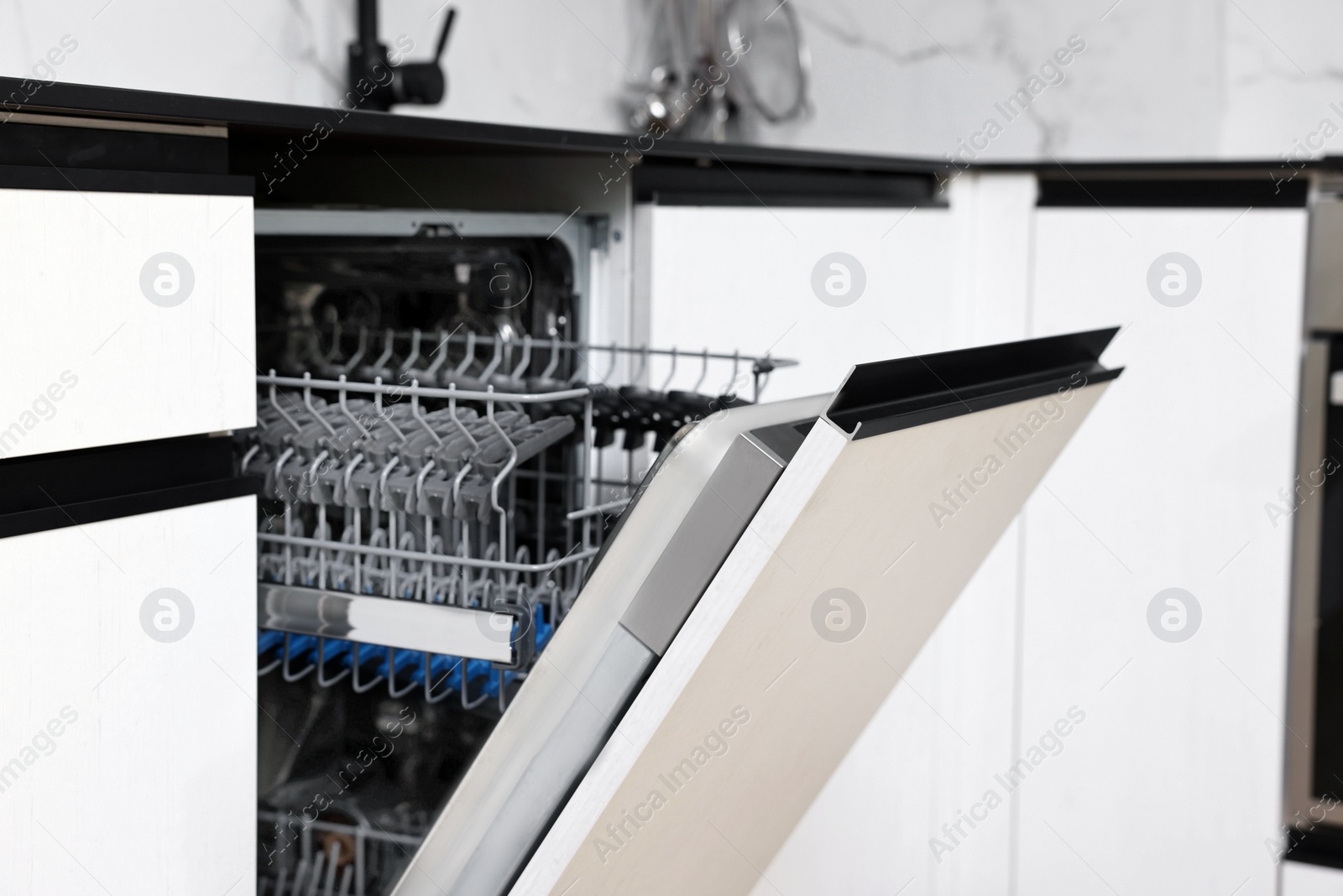 Photo of Built-in dishwasher with open door indoors. Home appliance