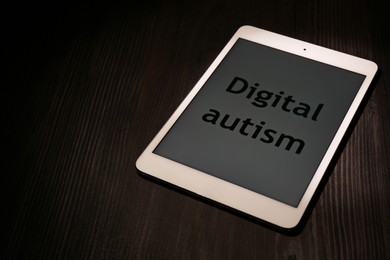 Photo of Tablet with phrase Digital Autism on wooden table, space for text. Addictive behavior