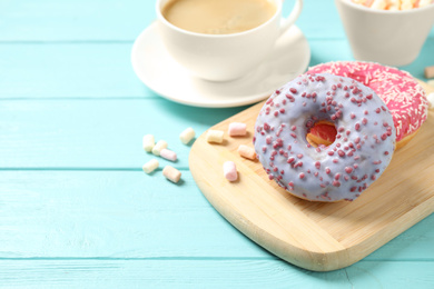 Photo of Delicious glazed donuts on blue wooden table. Space for text