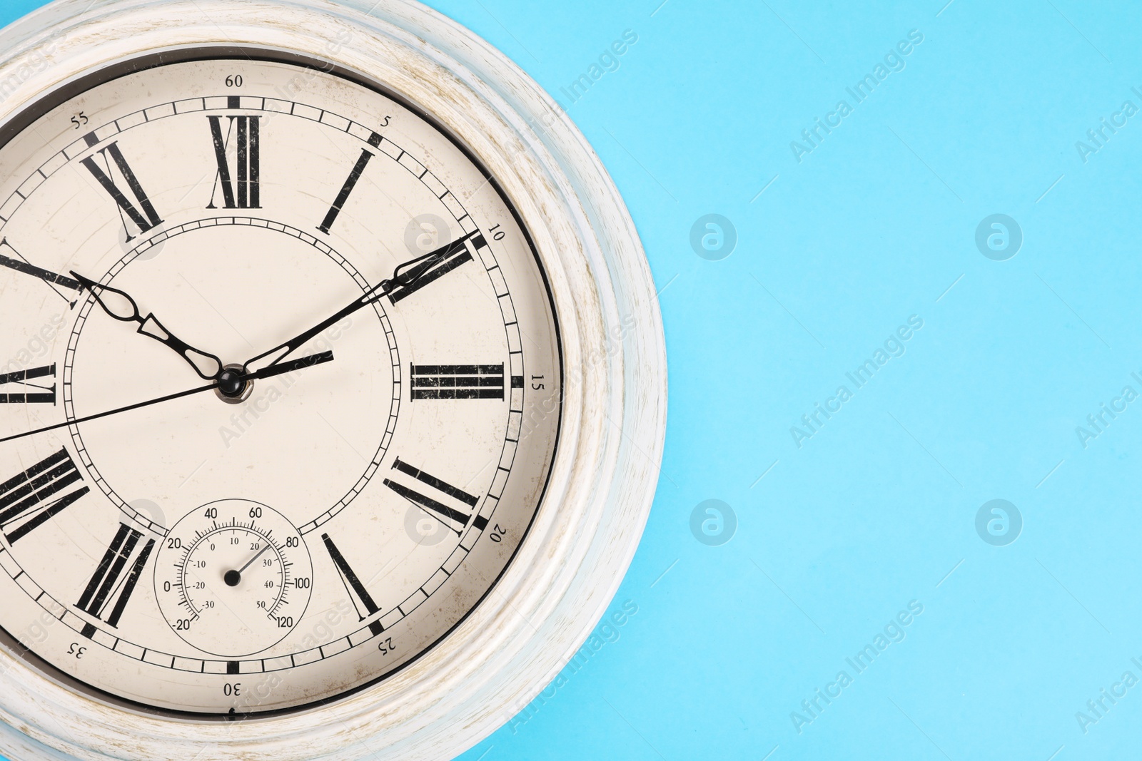 Photo of Stylish vintage wall clock on turquoise background, top view. Space for text