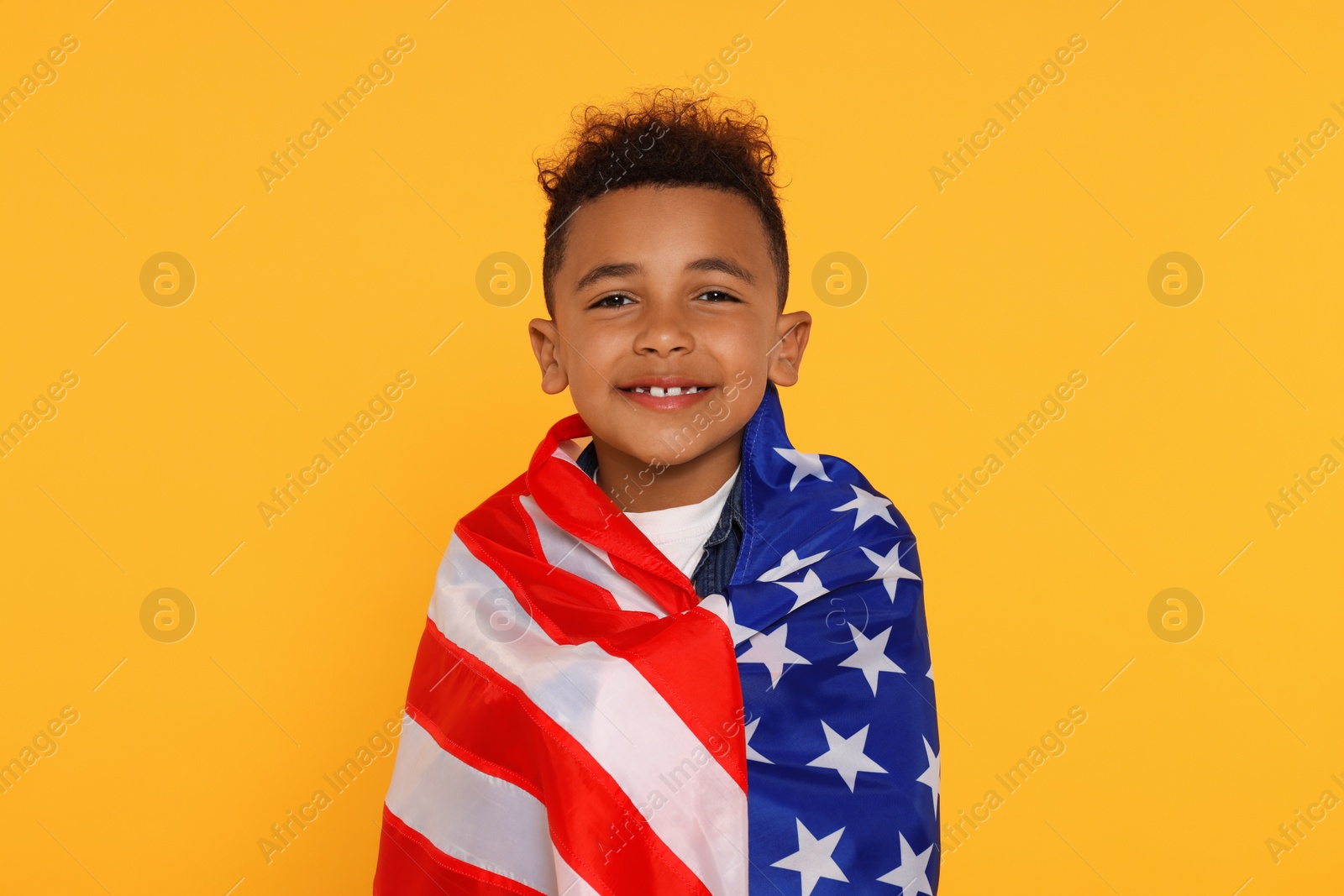 Photo of 4th of July - Independence Day of USA. Happy boy with American flag on yellow background