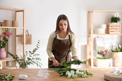 Photo of Florist making beautiful bouquet at table in workshop