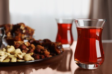 Photo of Glasses with tasty Turkish tea and sweets on brown table indoors