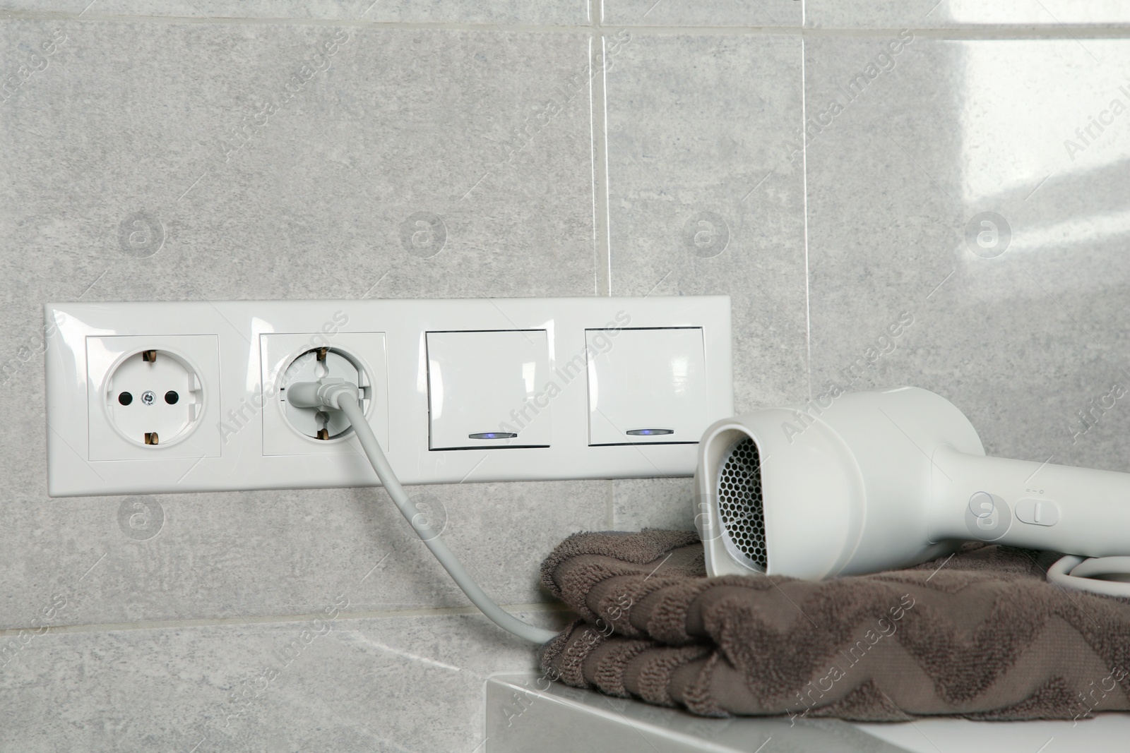 Photo of Hairdryer plugged into power socket on light grey wall
