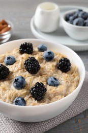 Photo of Tasty oatmeal porridge with blackberries and blueberries in bowl on table