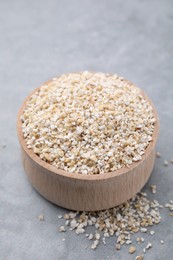 Photo of Raw barley groats in bowl on grey table, closeup