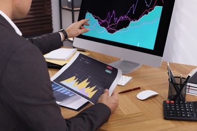 Photo of Businessman working with computer and graph in office, closeup. Forex trading