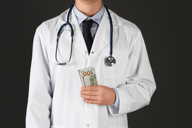 Photo of Doctor with bribe on black background, closeup. Corruption in medicine