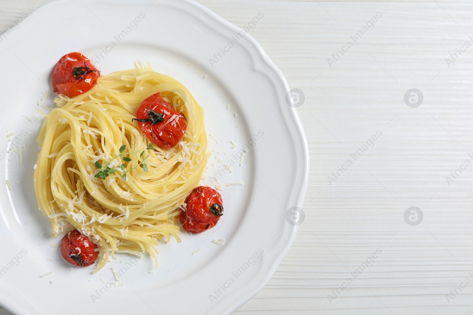 Photo of Tasty capellini with tomatoes and cheese on white wooden table, top view and space for text. Exquisite presentation of pasta dish