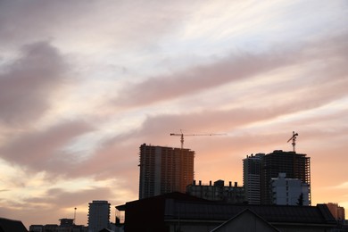 Photo of Tower cranes near unfinished buildings in city