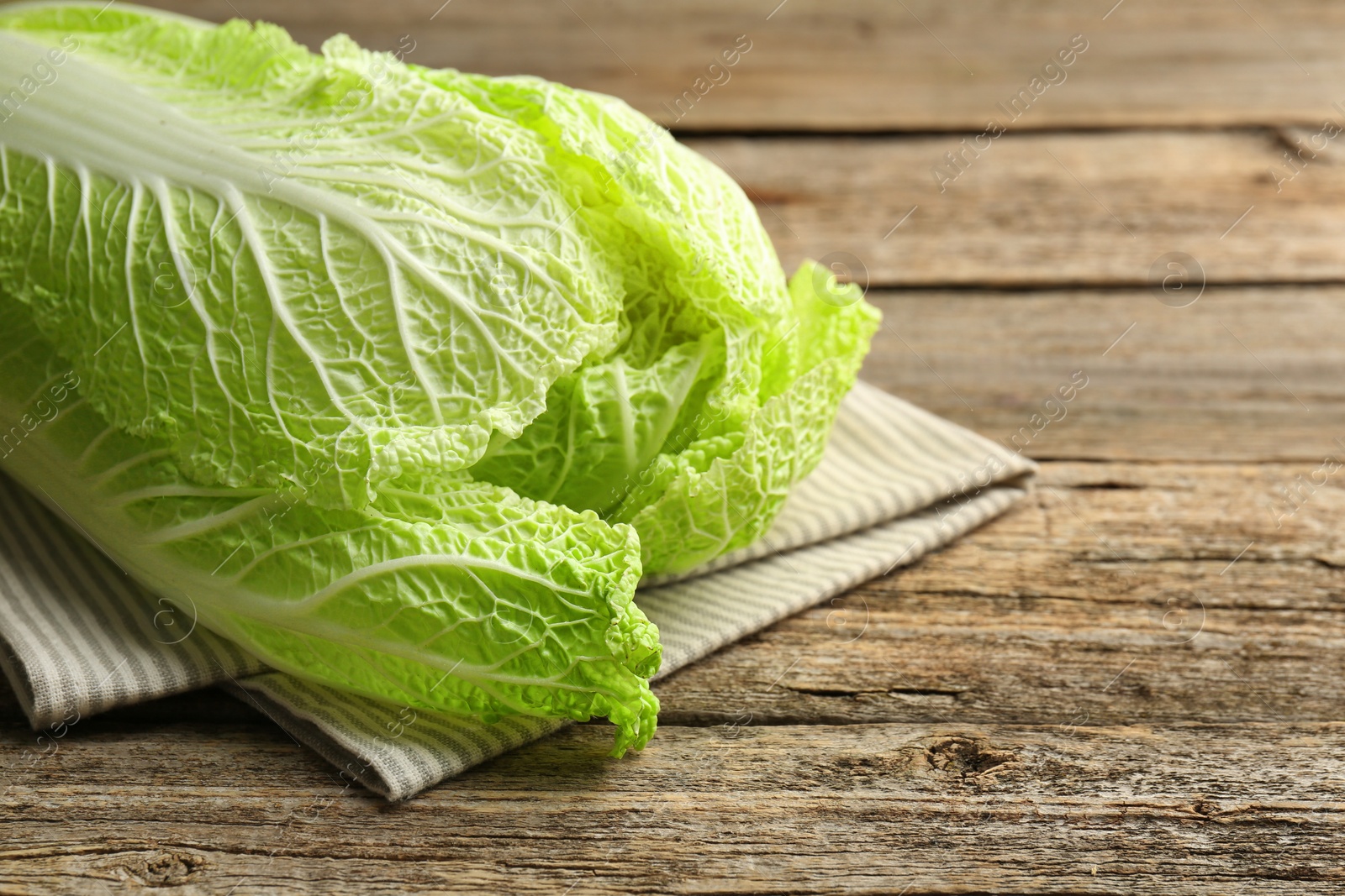 Photo of Fresh ripe Chinese cabbage on wooden table, closeup. Space for text