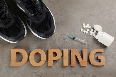 Photo of Word Doping, sport shoes and drugs on grey background, flat lay