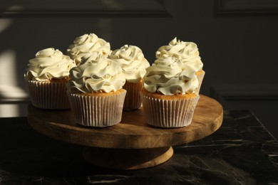 Photo of Tasty cupcakes with vanilla cream on black table, closeup