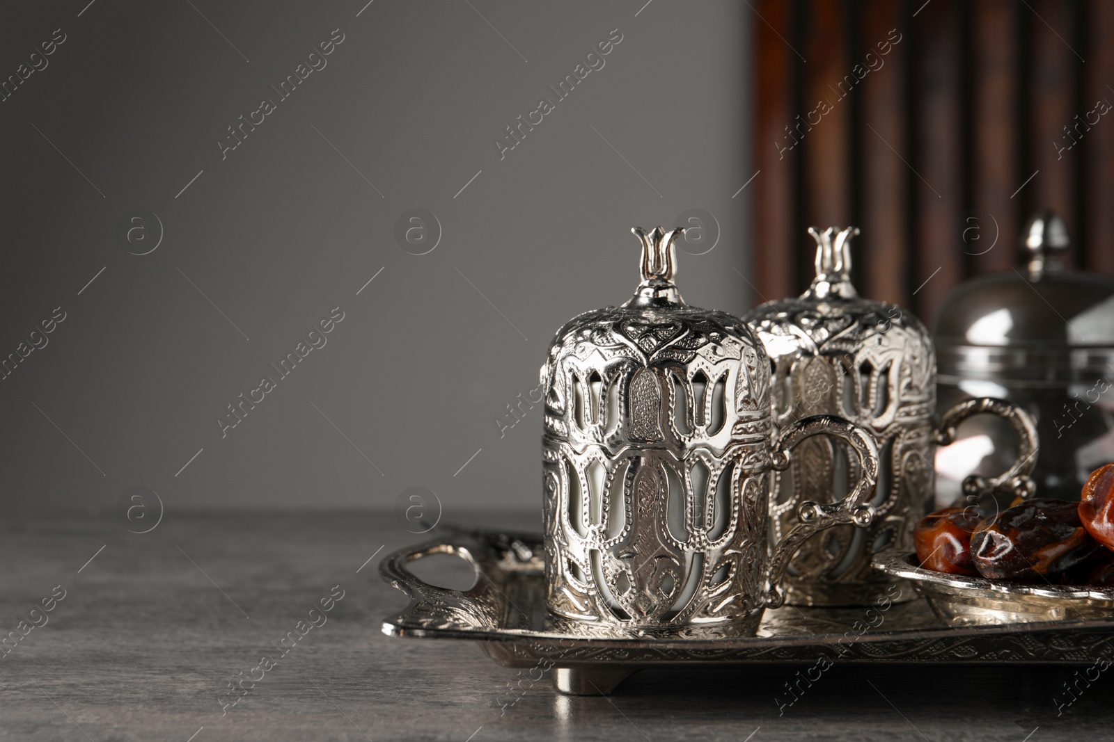 Photo of Tea and date fruits served in vintage tea set on grey textured table, space for text